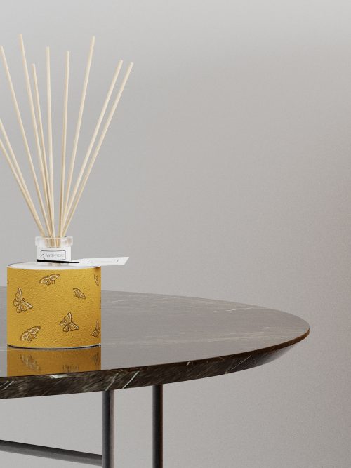 profumatore d'arredo aperto con bastoncini di bamboo poggiato su un raffinato tavolino moderno