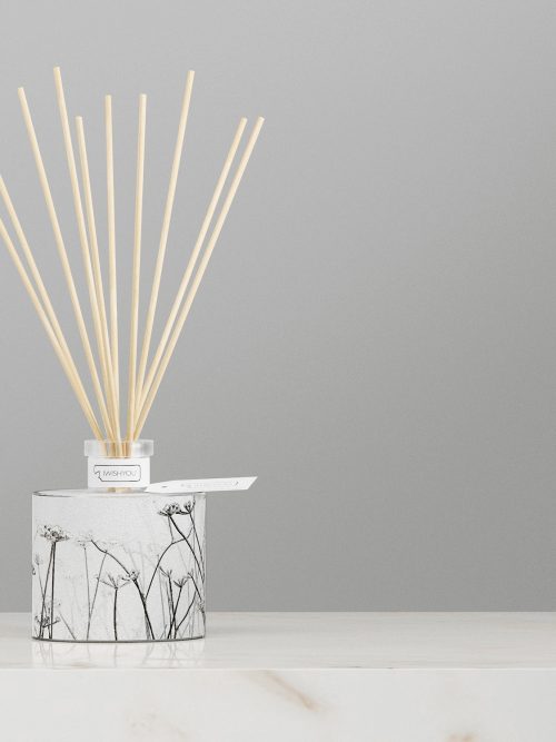 profumatore d'arredo aperto con bastoncini di bamboo poggiato su un raffinato tavolino moderno
